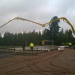 Betonipumppuauton puomi ulottuu kauas työmaalla metsän reunassa